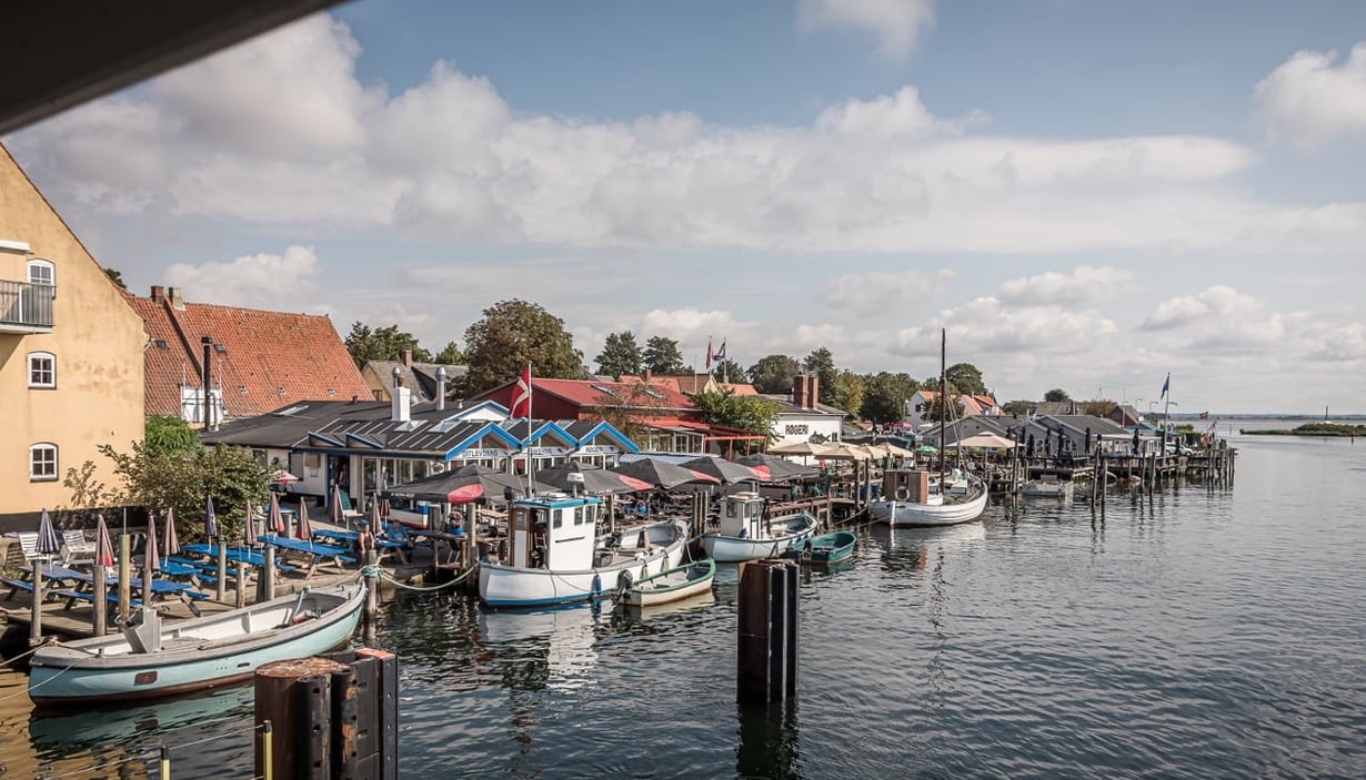 Maleriske Karrebæksminde med små båter og bygninger ved vannkanten.