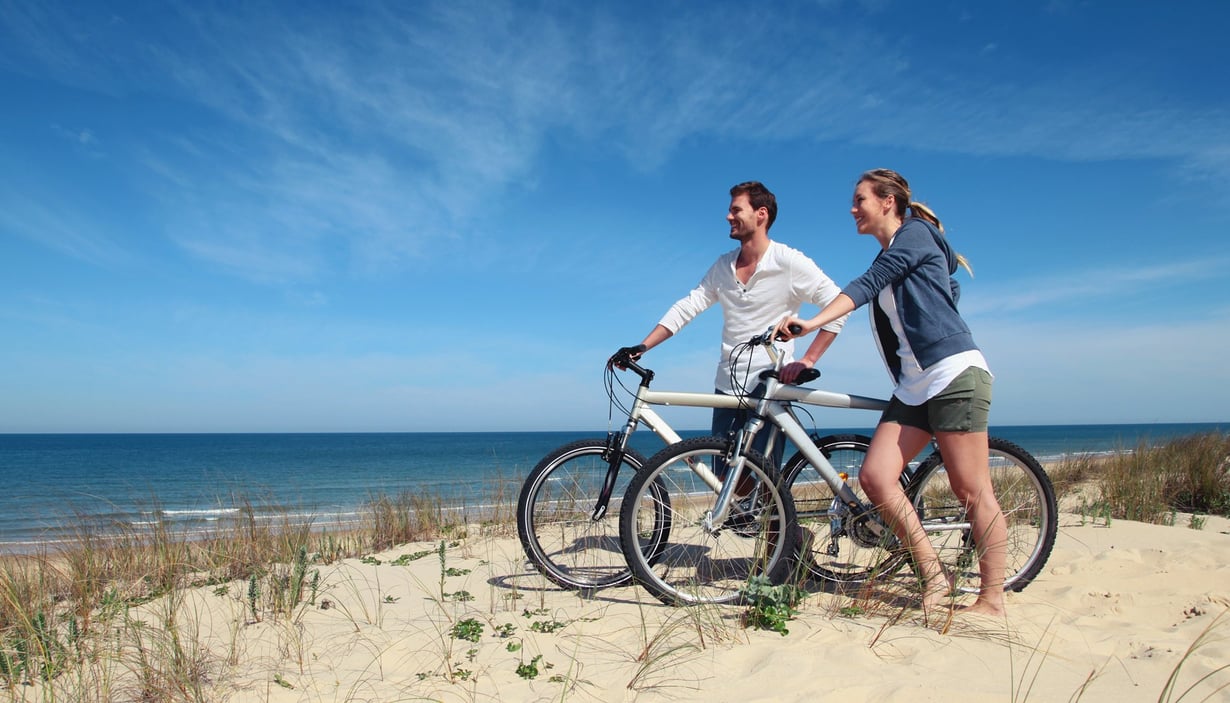 To personer med sykler på stranden.