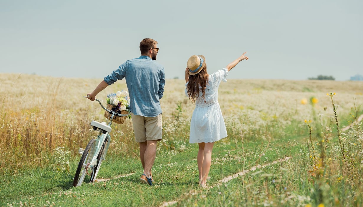 To personer med en sykkel på en sti ved et jorde.