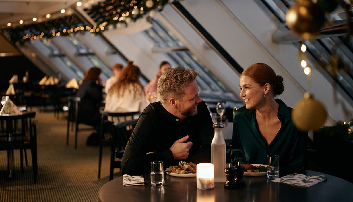 Folk som spiser på en restaurant med naturlig lys og dekorasjoner.
