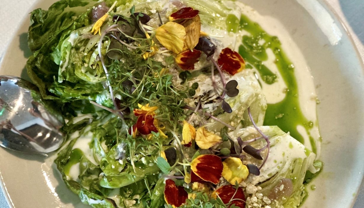 Tallerken med salat med forskjellige grønnsaker, mikrogrønt, spiselige blomster og grønn dressing