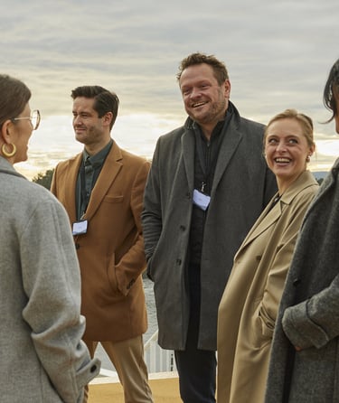 En gruppe mennesker i yttertøy som prater sammen på dekk under en konferanse