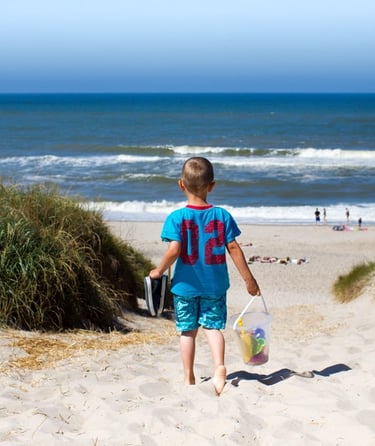 Barn som går ned en sandsti mot stranden.