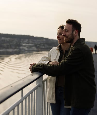 To personer som står på et dekk og ser ut over en vannmasse.