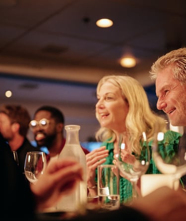 Venner samlet rundt et restaurantbord med vin og vann, og nyter en koselig kveld inne