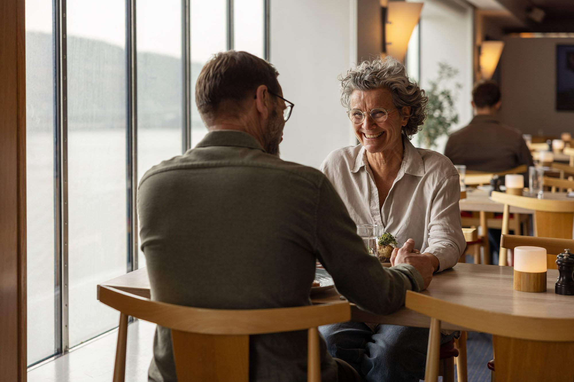 To personer som sitter ved et bord i en restaurant og holder hender.