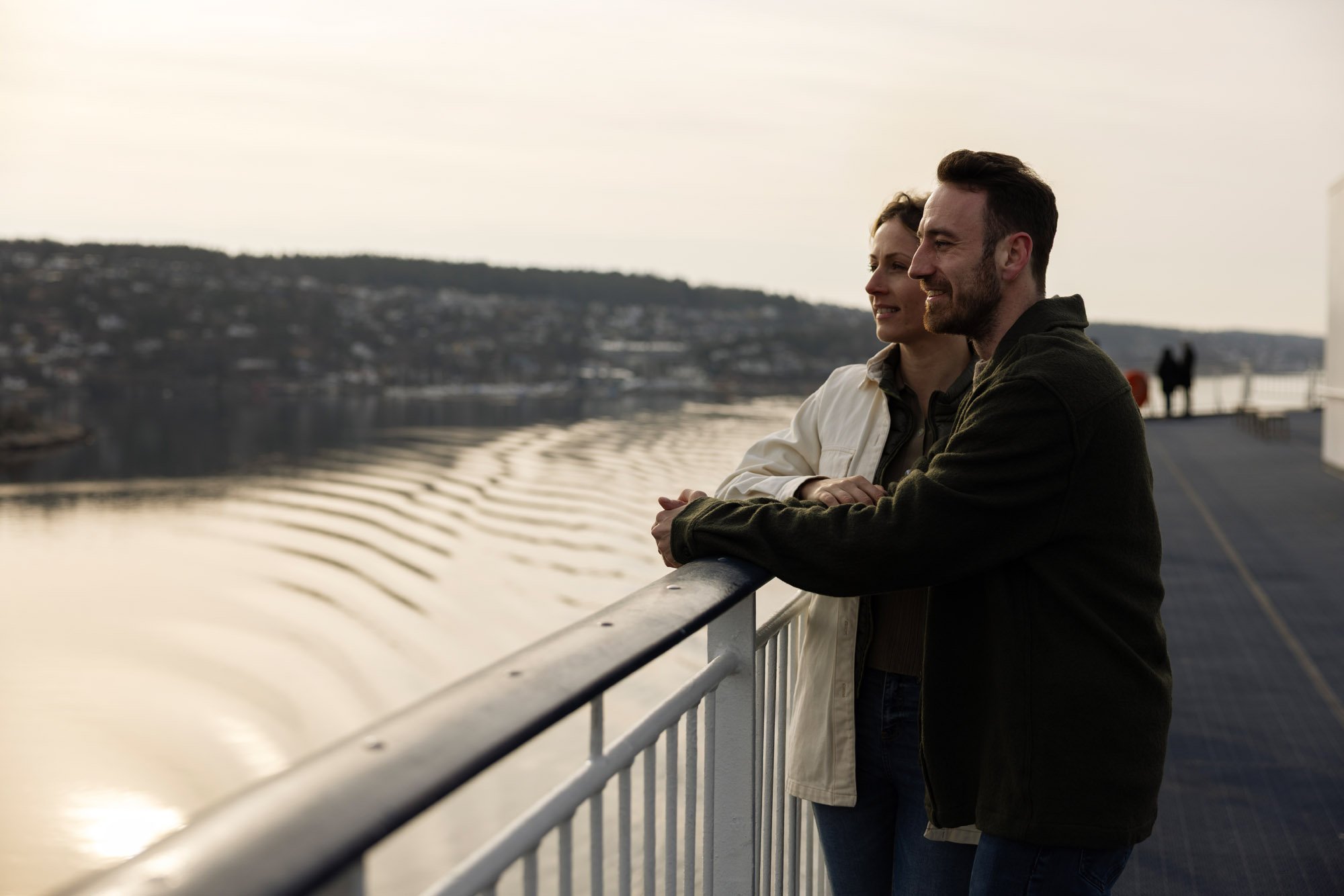 To personer som står på et dekk og ser ut over en vannmasse.