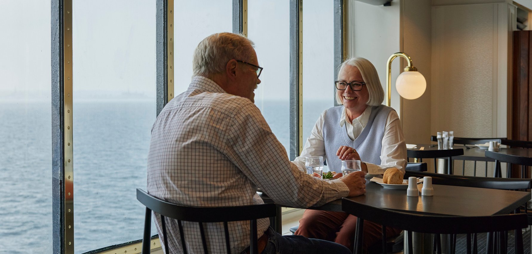 Seniorpar sitter ved bord med havutsikt