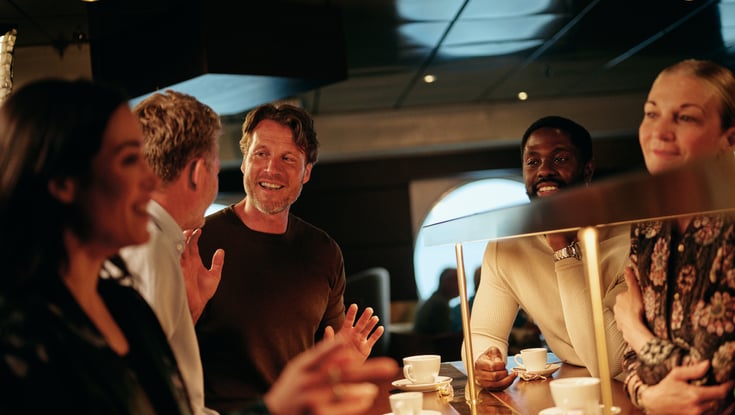 Gruppe mennesker som står rundt en disk i en kafé.