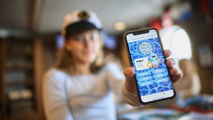 Person som holder en smarttelefon som viser en applikasjon eller nettside relatert til Matrosklubben.