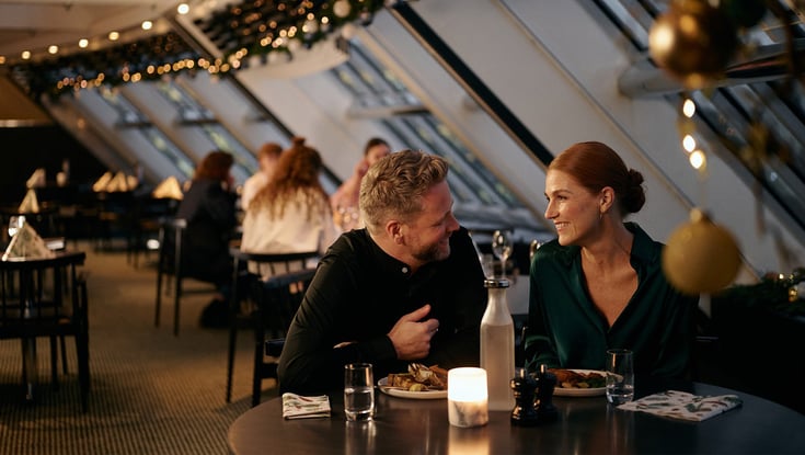 Folk som spiser på en restaurant med naturlig lys og dekorasjoner.