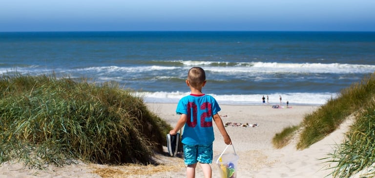 Barn som går ned en sandsti mot stranden.