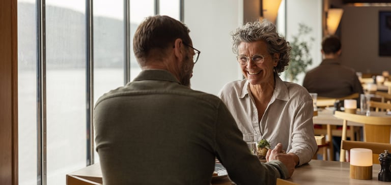 To personer som sitter ved et bord i en restaurant og holder hender.