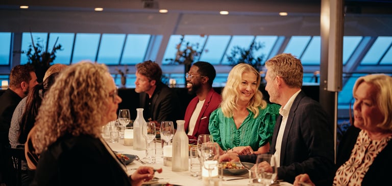 Middag ved solnedgang i lyst rom med store vinduer, lys og vinglass