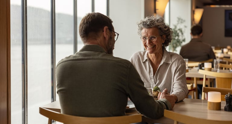 To personer som sitter ved et bord i en restaurant og holder hender.
