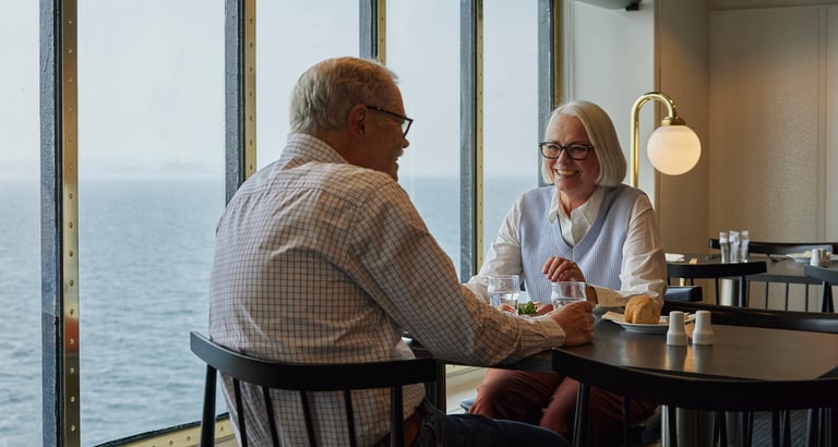 Seniorpar sitter ved bord med havutsikt