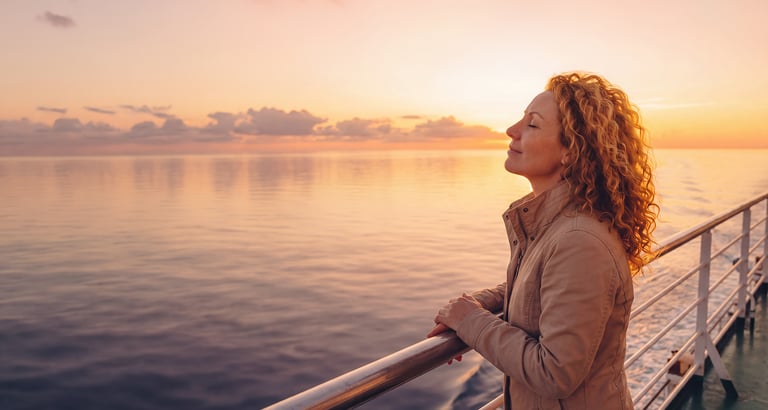 Ai bilde av dame på dekk i en rosa og oransj solnedgang