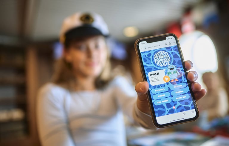 Person som holder en smarttelefon som viser en applikasjon eller nettside relatert til Matrosklubben.