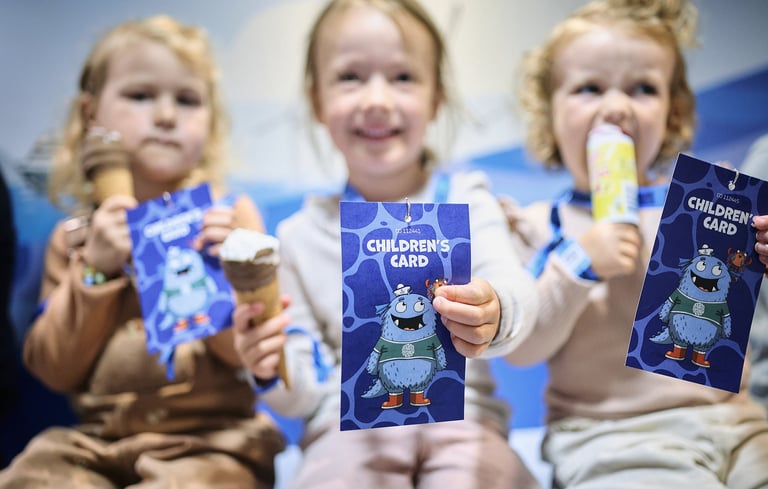 Tre barn som holder opp "Children's Card"-hefter med en tegneseriefigur i Matrosklubben.