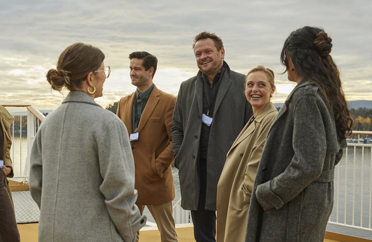 En gruppe mennesker i yttertøy som prater sammen på dekk under en konferanse