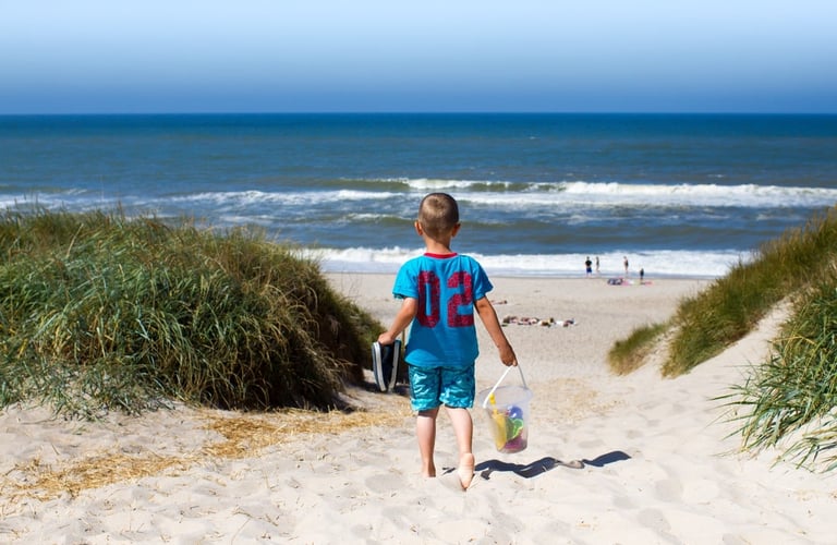 Barn som går ned en sandsti mot stranden.
