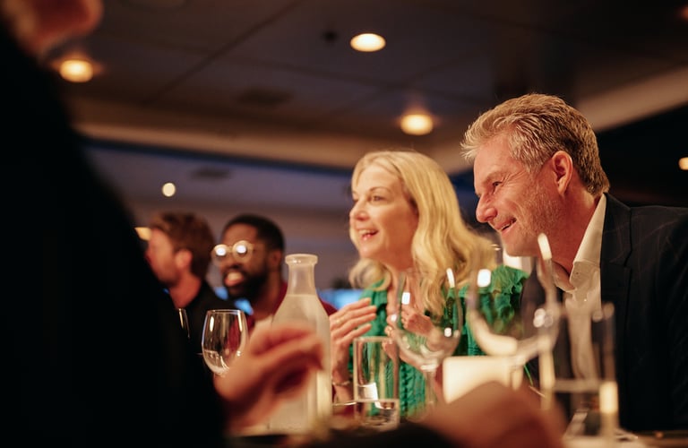 Venner samlet rundt et restaurantbord med vin og vann, og nyter en koselig kveld inne