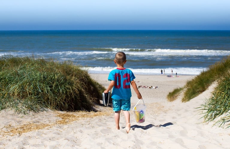 Barn som går ned en sandsti mot stranden.