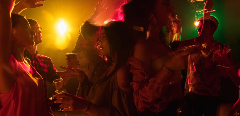En gruppe mennesker på en fest med fargerike lys.