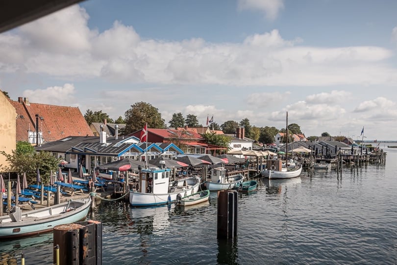 Maleriske Karrebæksminde med små båter og bygninger ved vannkanten.