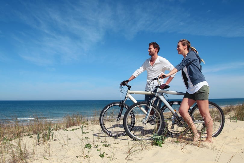 To personer med sykler på stranden.