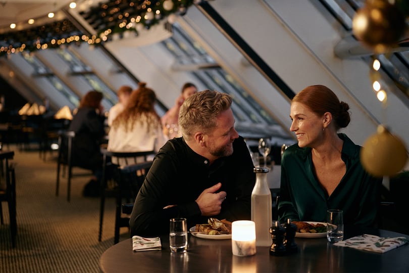 Folk som spiser på en restaurant med naturlig lys og dekorasjoner.